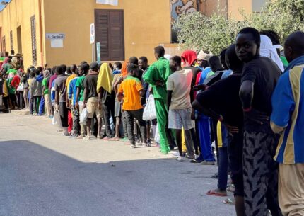 La fila di migranti per il cibo a Lampedusa.