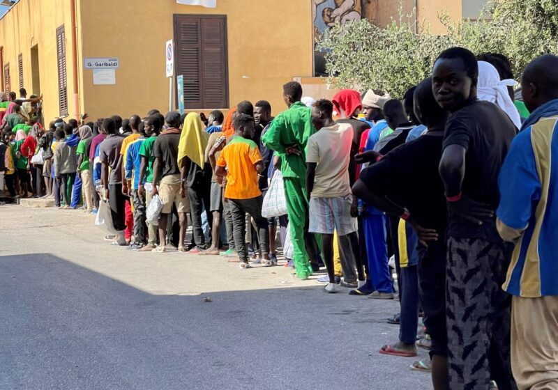 La fila di migranti per il cibo a Lampedusa.